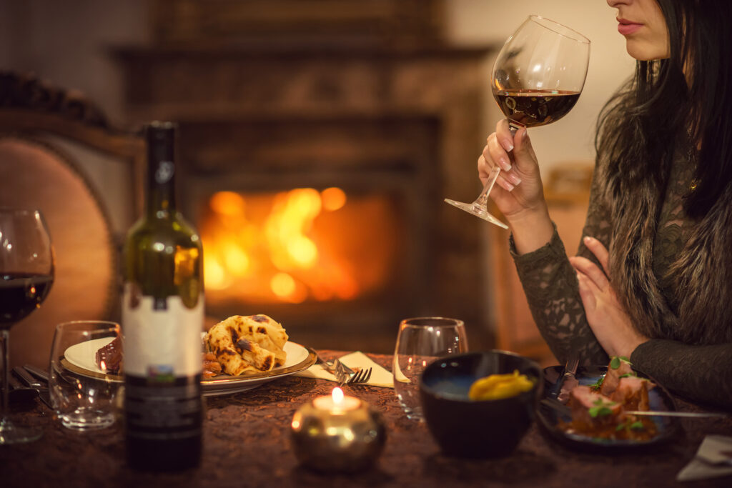 Couple enjoying wine and dinner by fireplace in Aspen Luxury Rental during winter